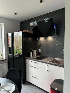 uma cozinha com armários brancos e uma parede preta em Hugo em Jēkabpils