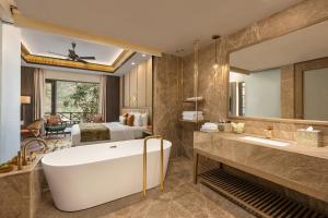 ein Bad mit einer Badewanne und ein Schlafzimmer in der Unterkunft Taj Corbett Resort and Spa Uttarakhand in Rāmnagar