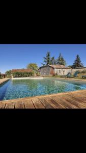 une grande piscine d'eau avec une maison en arrière-plan dans l'établissement Chalet 2 pers « chez Jojo », à Sérignac