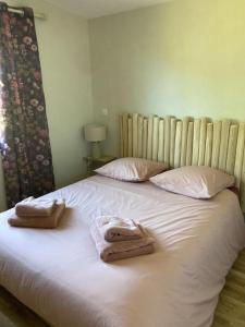 1 cama con 2 toallas y almohadas en Chalet 2 pers « chez Jojo » en Sérignac