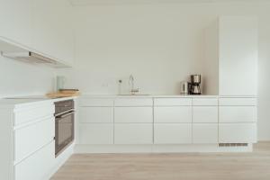 a white kitchen with white cabinets and appliances at Nordic Swan Aparthotel with Panoramic Seaview in Tórshavn