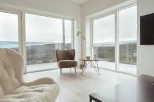 a living room with a chair and a table and windows at Nordic Swan Aparthotel with Panoramic Seaview in Tórshavn