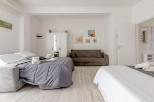 1 dormitorio blanco con 2 camas y sofá en Il Barone Rosso B&B, en Lecce
