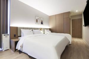 a large white bed in a hotel room at Wonju Brown Dot Hotel Corporate city in Wonju