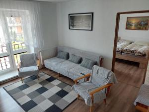 een woonkamer met een bank, stoelen en een spiegel bij Vaclavskeho Apartment Medzilaborce in Medzilaborce