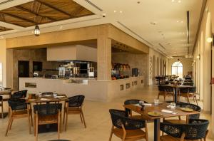 um restaurante com mesas e cadeiras e uma cozinha em Bab Al Nojoum Bateen Liwa em Liwa