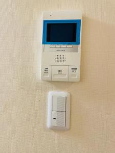 un dispositivo electrónico con un monitor y una caja en la pared en Uhome Kamiitabashi Apartment, en Tokio
