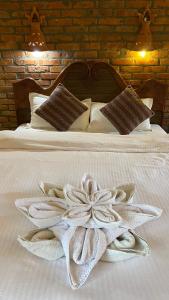 a white blanket with a flower on a bed at Chautari Garden Resort in Sauraha