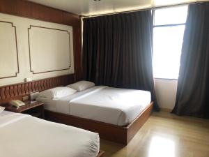 a hotel room with two beds and a window at Malaysia Hotel Bangkok in Bangkok