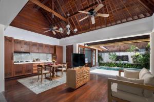 a kitchen and living room with a table and a ceiling fan at The Alantara Sanur in Sanur