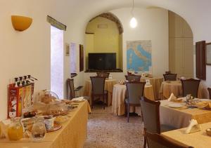 una sala da pranzo con tavoli, sedie e TV di Hotel San Giuseppe a Gerace