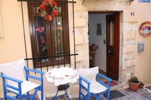 a table and chairs on a porch with a door at Anemones Rooms in Chania