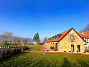 una casa de piedra con techo naranja en un campo verde en DRIEHOF Lifestyle Comfort Apartment 3, en Tecklenburg