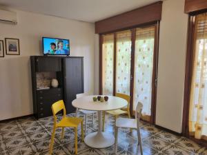 Appartamenti Aurora في غرادو: غرفة طعام مع طاولة بيضاء وكراسي صفراء