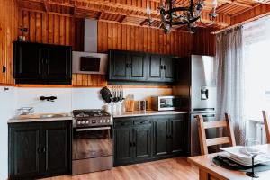 a kitchen with black cabinets and a stove at Tatra House z Jacuzzi in Poronin