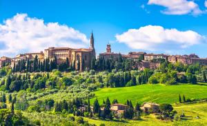 a castle on top of a green hill with trees at Renaissance House in Pienza