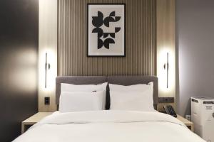 um quarto com uma cama grande com lençóis brancos e almofadas em Wonju Brown Dot Hotel Corporate Business em Wonju