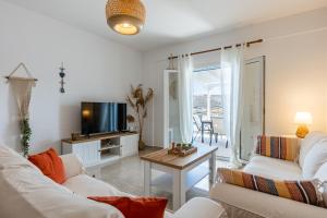 a living room with two white couches and a tv at My Kythnos House in Kithnos