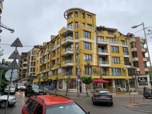 un edificio amarillo con coches estacionados frente a él en Niko's deluxe apartment en Sofía