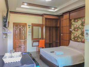 a bedroom with a bed and a desk and a table at โรงแรมสบาย พาเลซ in Nakhon Si Thammarat