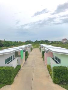 a row of white buildings with green plants at โรงแรมสบาย พาเลซ in Nakhon Si Thammarat