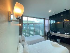 a hotel room with two beds and a desk at โรงแรมสบาย พาเลซ in Nakhon Si Thammarat