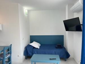 Un dormitorio con una cama azul y una mesa en Apartamentos Can Marsalet en Portocolom