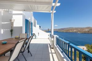 balkon ze stołem i krzesłami oraz widokiem na wodę w obiekcie My Kythnos House w mieście Kitnos