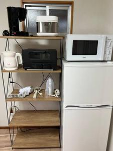 a kitchen with a microwave and a refrigerator at 駅徒歩２分の貸切一軒家【Villa Kokusai】 in Naha