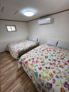 a bedroom with two beds and two windows at 駅徒歩２分の貸切一軒家【Villa Kokusai】 in Naha