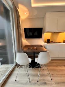 duas cadeiras brancas e uma mesa numa cozinha em DRIEHOF LifeStyle Comfort Apt 4 em Tecklenburg