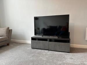 uma televisão de ecrã plano numa bancada numa sala de estar em Comfortable City Apartment em Derby