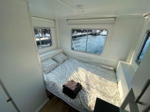 a small room with a bed and two windows at Casa flotante con terraza en un marco inigualable in Ribadeo