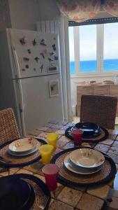 a table with plates and cups and a refrigerator at Casa sul mare in Porto Torres
