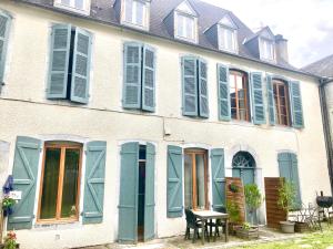 ein Haus mit blauen Fensterläden und einem Tisch davor in der Unterkunft Une maison de famille in Oloron-Sainte-Marie