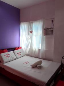 a bed with red writing on it with a window at WJV INN NAGA in Tina-an