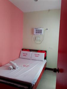 a small room with a bed with red and white walls at WJV INN NAGA in Tina-an