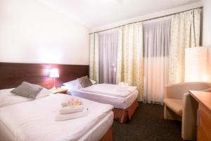 um quarto de hotel com duas camas e uma cadeira em Penzión Ľadoveň SKVELÁ KUCHYŇA A RODINNÁ ATMOSFÉRA em Martin