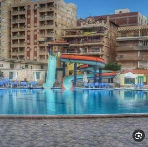 a swimming pool with a water slide in front of a building at Alzohour Family condo with panoramic sea view in Alexandria