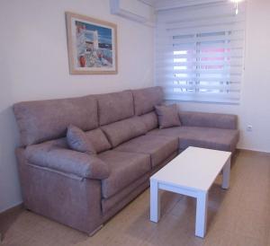 ein Wohnzimmer mit einem braunen Sofa und einem weißen Tisch in der Unterkunft Tui Casa in Puerto Marino