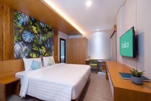 a bedroom with a bed and a desk and a tv at Aralea Coliving in Denpasar