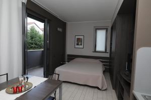 a bedroom with a bed and a table and a window at Hotel Residence Aurora in Paderno Dugnano