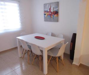 einem weißen Tisch mit weißen Stühlen und einer roten Platte darauf in der Unterkunft Tui Casa in Puerto Marino