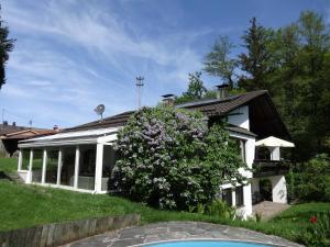 ein weißes Haus mit einem blühenden Busch davor in der Unterkunft Gästehaus Ehrlich in Prien am Chiemsee