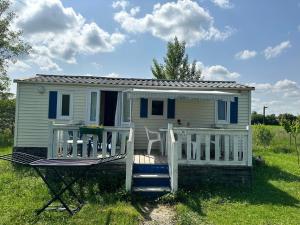 uma pequena casa branca com um alpendre e um deque em LES EYCHECADOUS em Artigat