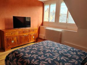 - une chambre avec un lit et une télévision sur une commode dans l'établissement L'Escale, chambres chez l'habitant, au Mans