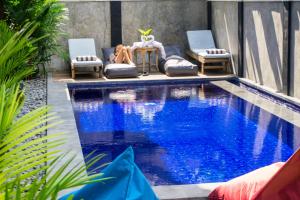 a small swimming pool with two chairs and a table at The Lucky Canggu in Canggu