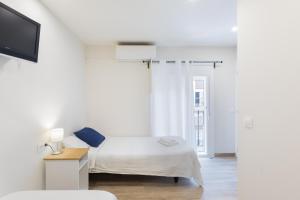 a white bedroom with a bed and a tv at Hostal Oliveta in Barcelona