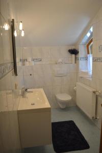 Baño blanco con lavabo y aseo en Haus letzte Rose en Rieden am Forggensee
