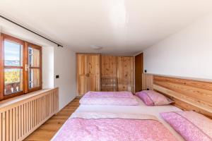 two beds in a bedroom with wooden walls and windows at Malgorerhof Mathilde in San Genesio Atesino